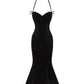 Black velvet evening gown with thin halter straps on a white background