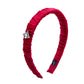 Red ruched silk headband with a decorative triangle shaped gemstone on a white background