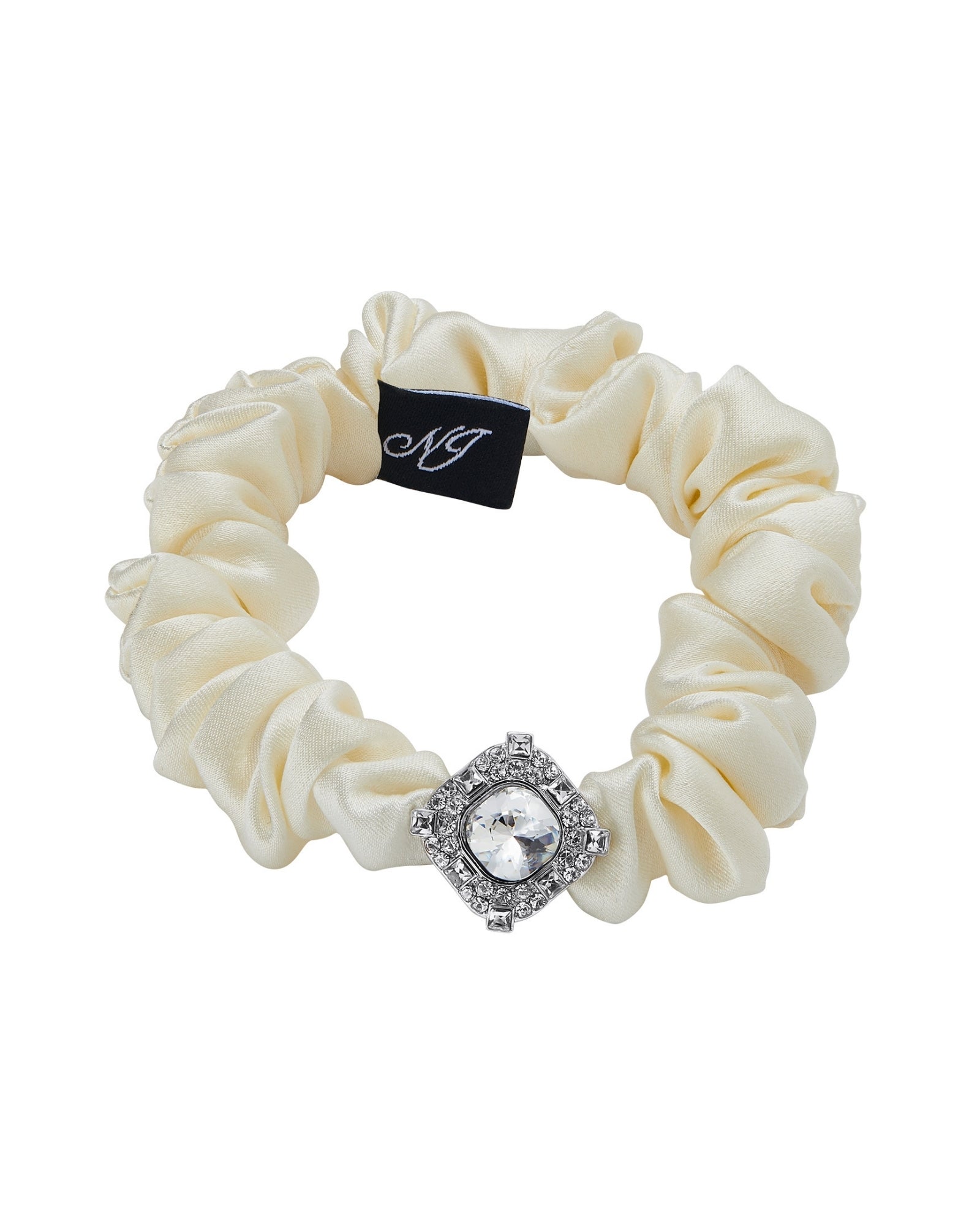 A white silk scrunchie accented with a silver diamond-shaped embellishment on a white background.
