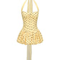 Yellow polka dot mini dress with thin straps on a white background
